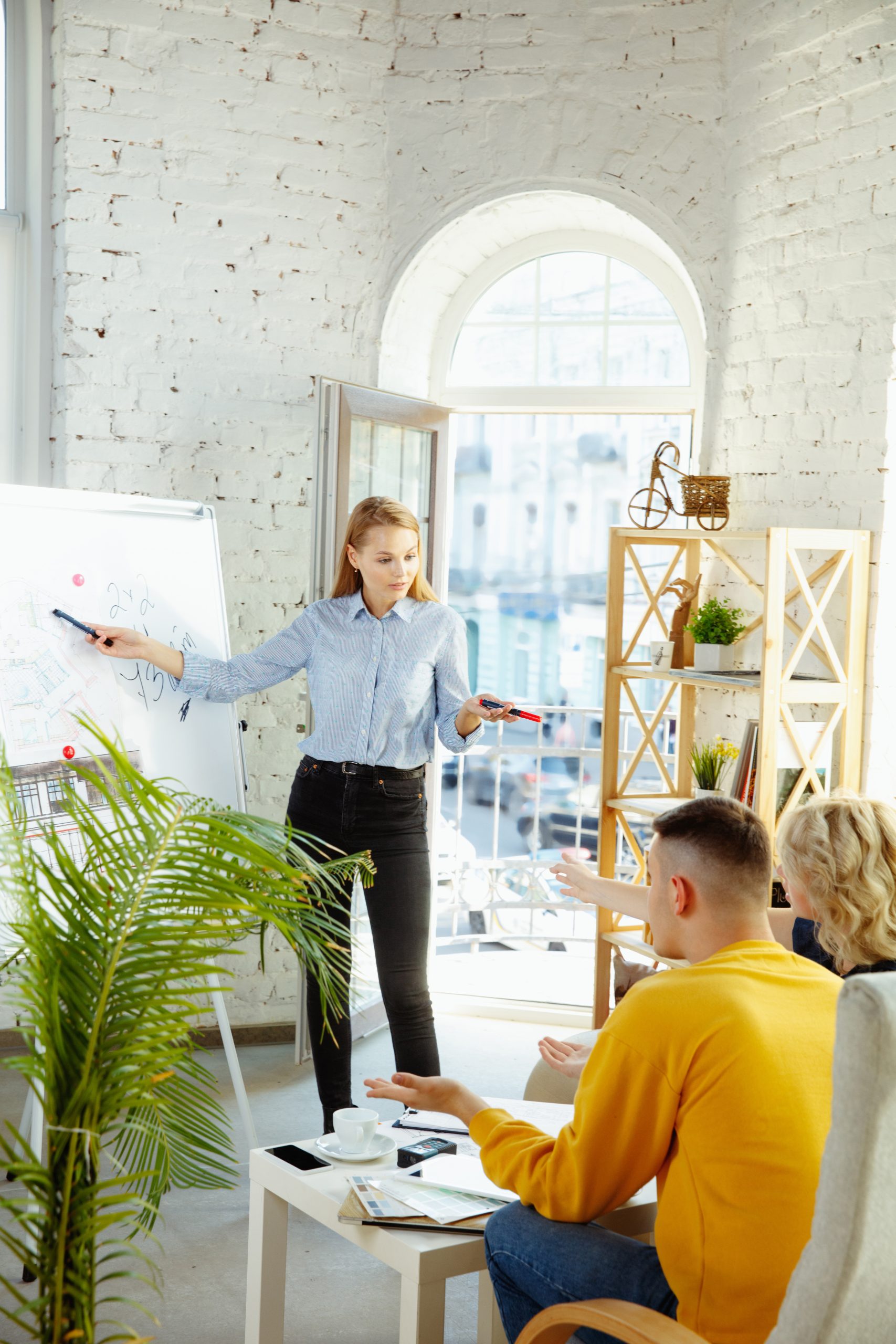 Interior designer working with young couple. Lovely family and professional designer or architector discussing conept of future interior, working with colour palette, room drawings in modern office.