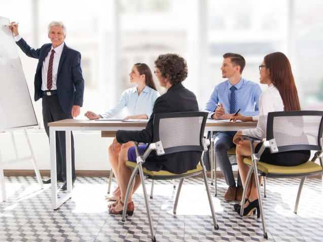 Smiling senior businessman conducting presentation in front of coworkers. Aged financial manager explaining new strategy to colleagues.
Business presentation concept